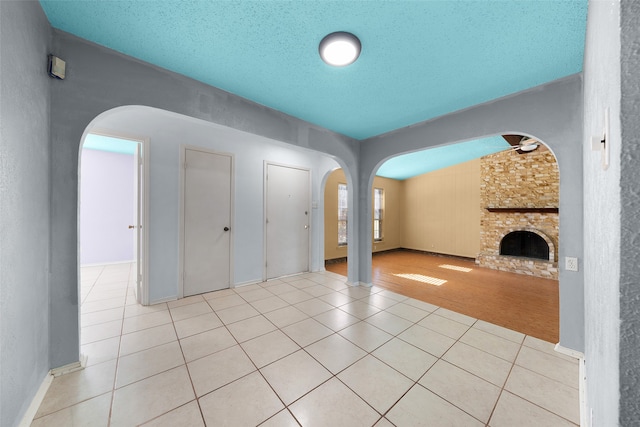 unfurnished living room with a fireplace, light tile patterned floors, and a textured ceiling