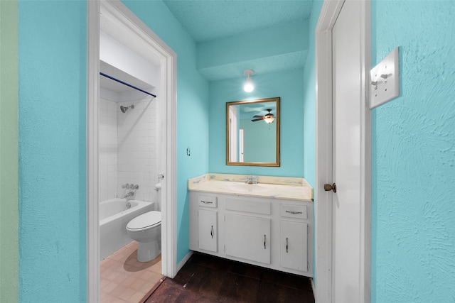 full bathroom featuring vanity, a textured ceiling, tiled shower / bath combo, ceiling fan, and toilet