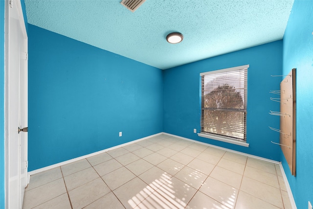 empty room with light tile patterned floors and a textured ceiling