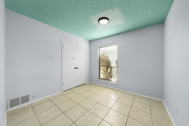 unfurnished room featuring light tile patterned floors and a textured ceiling