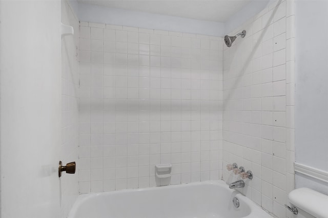 bathroom featuring toilet and tiled shower / bath