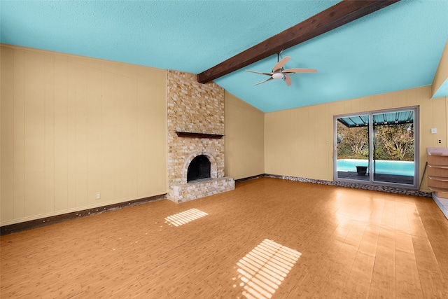 unfurnished living room featuring vaulted ceiling with beams, ceiling fan, a fireplace, and light hardwood / wood-style floors