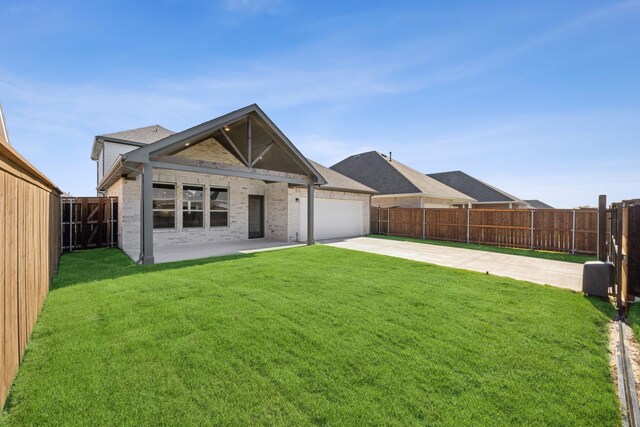 back of property featuring a garage, a patio area, and a lawn