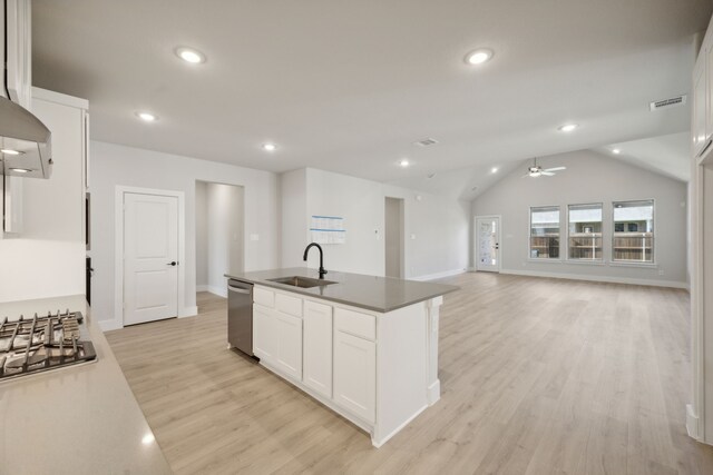 kitchen featuring sink, stainless steel appliances, vaulted ceiling, a center island with sink, and white cabinets