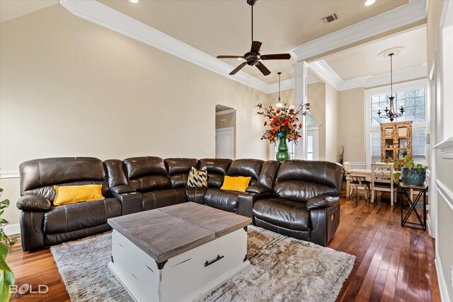 living room featuring dark wood-type flooring, ceiling fan with notable chandelier, and ornamental molding