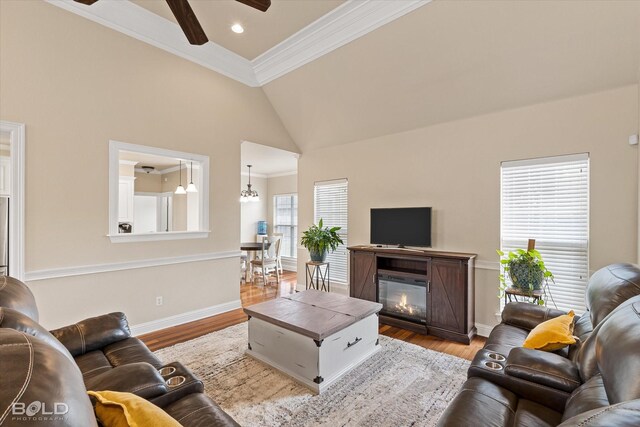 living room with ceiling fan, crown molding, high vaulted ceiling, and light hardwood / wood-style flooring