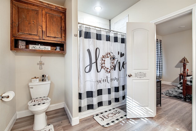 bathroom with hardwood / wood-style floors, toilet, and curtained shower