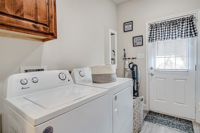 laundry area featuring cabinets, light wood-type flooring, and separate washer and dryer