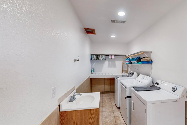 clothes washing area featuring washing machine and clothes dryer, sink, and light tile patterned flooring