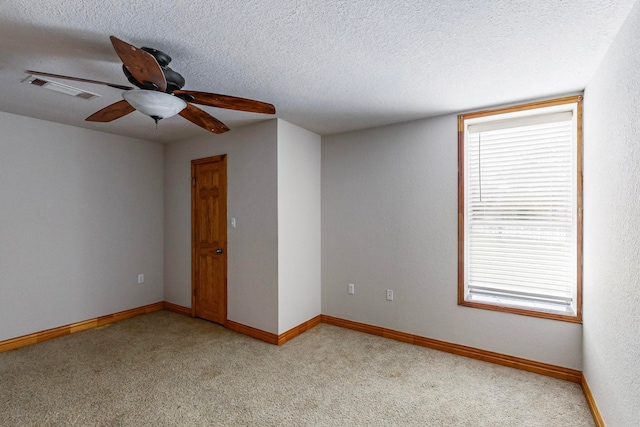 empty room featuring ceiling fan, a textured ceiling, and light carpet