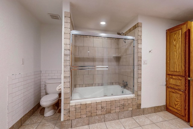 bathroom with tile patterned floors, combined bath / shower with glass door, and toilet