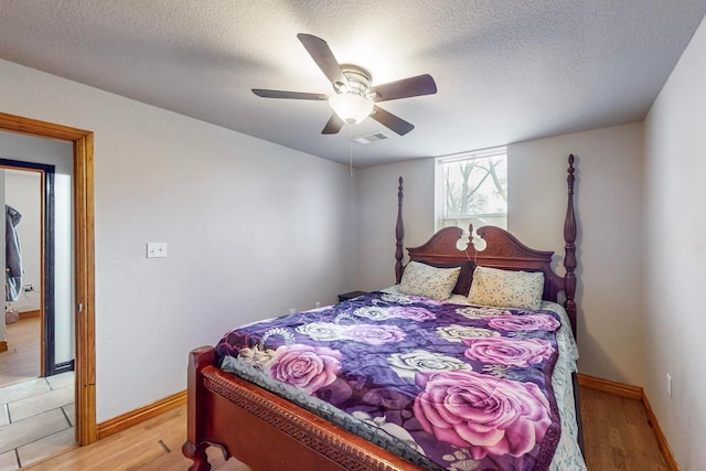 bedroom with ceiling fan, a textured ceiling, and light hardwood / wood-style flooring