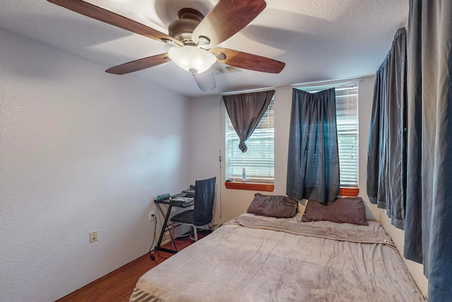 bedroom featuring hardwood / wood-style flooring, ceiling fan, and a textured ceiling