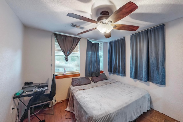 bedroom featuring hardwood / wood-style flooring, ceiling fan, and a textured ceiling