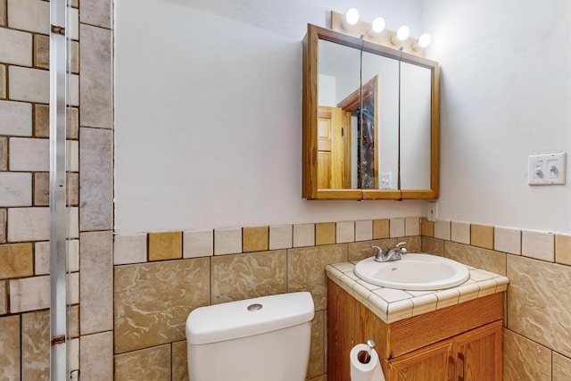 bathroom with vanity, toilet, and tile walls