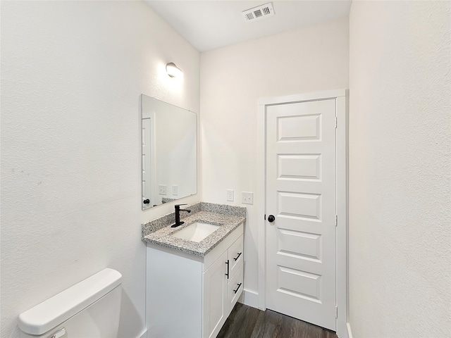 bathroom with toilet, vanity, and hardwood / wood-style flooring