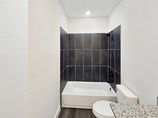 bathroom featuring hardwood / wood-style floors, tiled shower / bath combo, and toilet