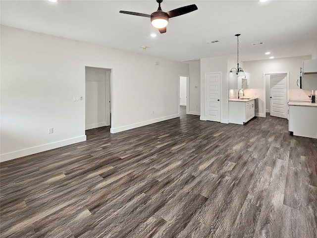 unfurnished living room with ceiling fan, dark wood-type flooring, and sink