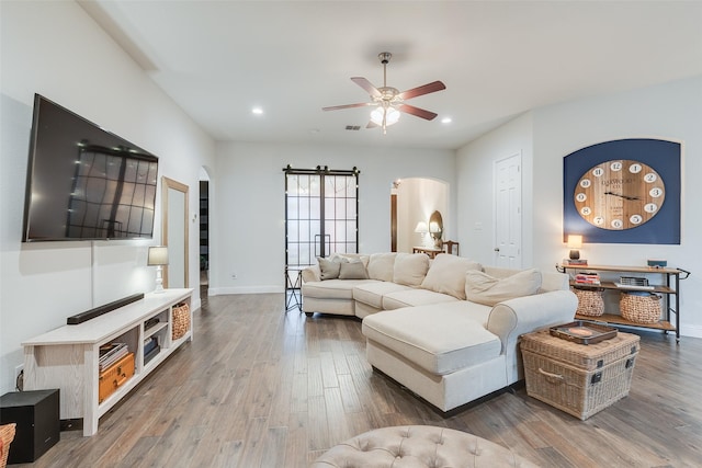 living room with recessed lighting, wood finished floors, arched walkways, and baseboards