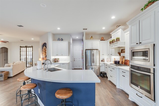 living area featuring a ceiling fan, recessed lighting, light wood-style floors, a fireplace, and baseboards