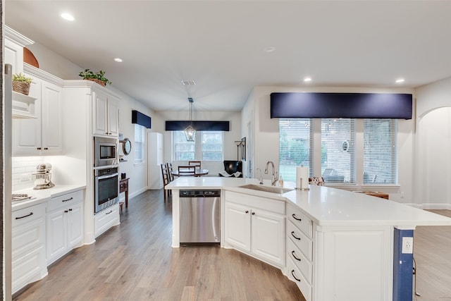 kitchen featuring light wood finished floors, a sink, light countertops, appliances with stainless steel finishes, and white cabinetry