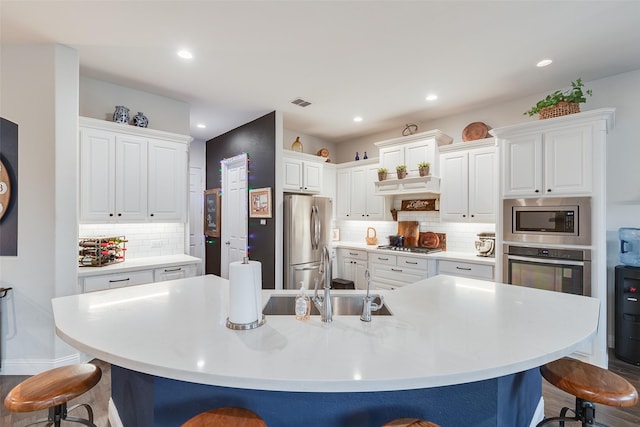 kitchen featuring appliances with stainless steel finishes, white cabinetry, a kitchen breakfast bar, and a sink