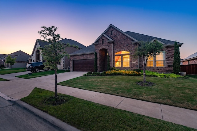 view of front of home with brick siding, a garage, driveway, and a front yard