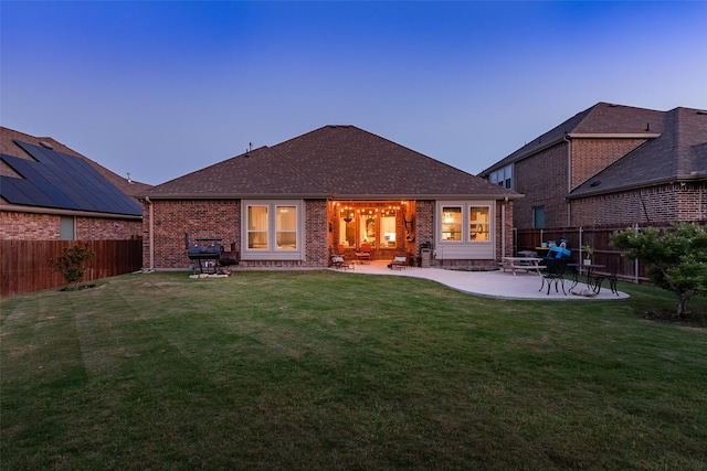 back of house featuring a patio, brick siding, a fenced backyard, and a lawn