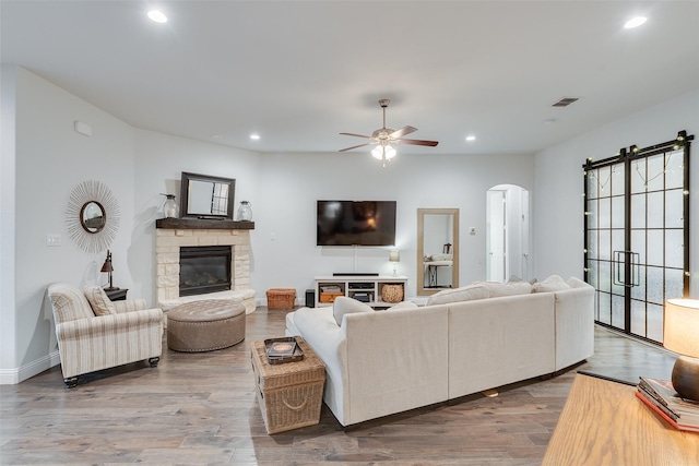 living area featuring arched walkways, visible vents, recessed lighting, and wood finished floors