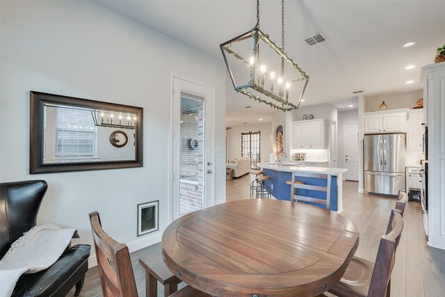 kitchen with a breakfast bar, light wood-style flooring, appliances with stainless steel finishes, white cabinets, and a sink