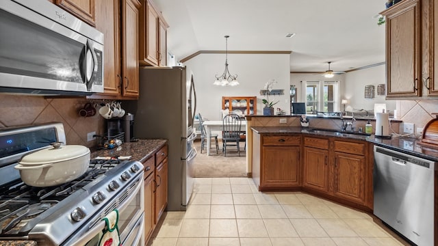 kitchen with ceiling fan with notable chandelier, stainless steel appliances, sink, light tile patterned floors, and lofted ceiling