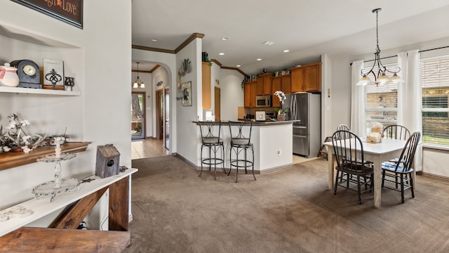 carpeted dining space with crown molding and a chandelier