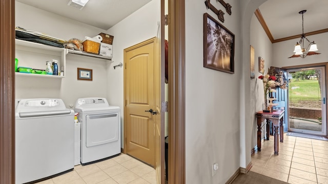 washroom featuring a chandelier, separate washer and dryer, crown molding, and light tile patterned flooring