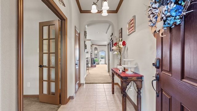 entryway featuring crown molding, light carpet, and a chandelier