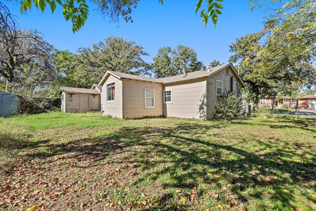 rear view of property with a storage shed and a yard