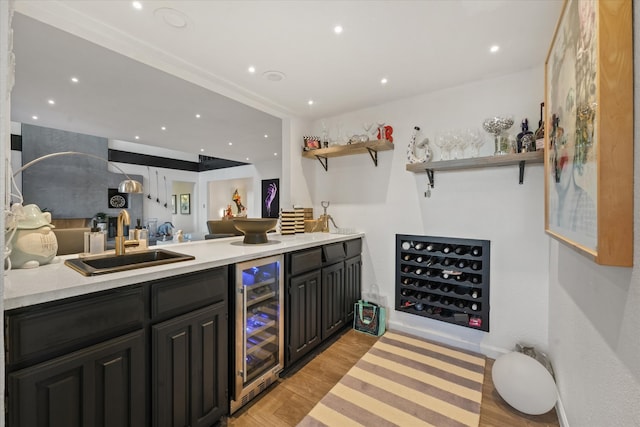 bar featuring sink, beverage cooler, and light hardwood / wood-style flooring