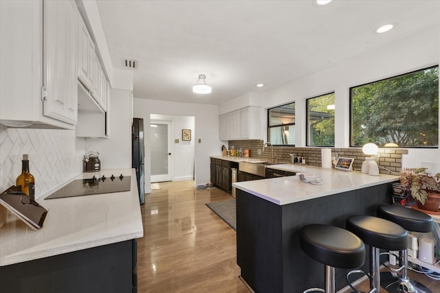 kitchen featuring white cabinets, light wood-type flooring, a breakfast bar area, and sink