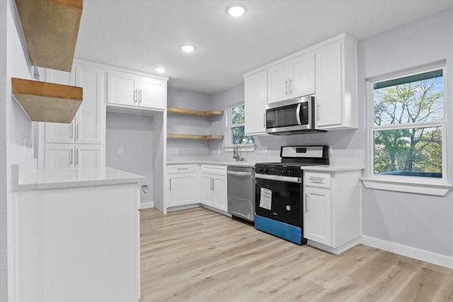 kitchen with white cabinetry, stainless steel appliances, sink, and light hardwood / wood-style floors