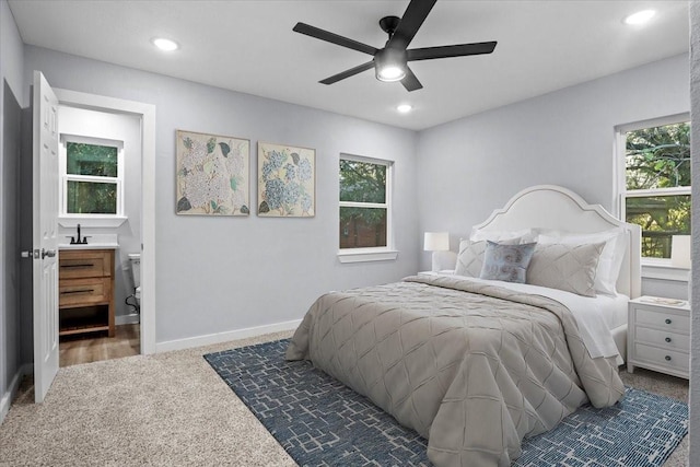 bedroom featuring ceiling fan, ensuite bathroom, and dark colored carpet