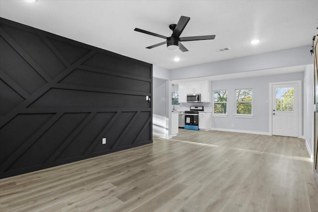 unfurnished living room featuring ceiling fan and light wood-type flooring