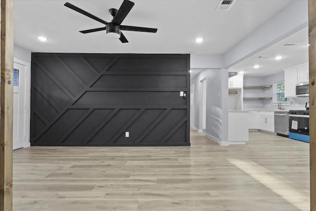 interior space with ceiling fan, light hardwood / wood-style floors, white cabinets, and appliances with stainless steel finishes