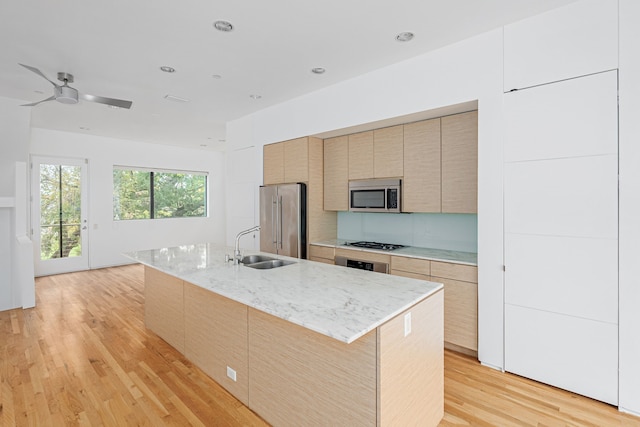 kitchen featuring ceiling fan, an island with sink, stainless steel appliances, and light hardwood / wood-style floors