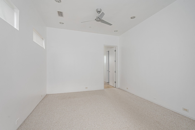 spare room with ceiling fan and light carpet