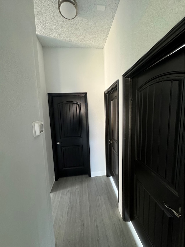 hallway with light hardwood / wood-style flooring and a textured ceiling