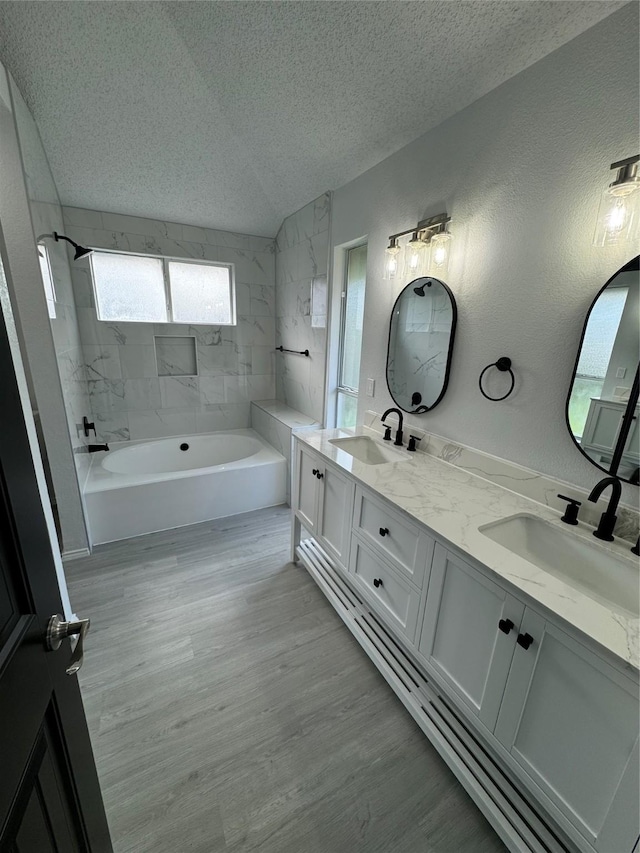 bathroom featuring a textured ceiling, vanity, tiled shower / bath combo, and hardwood / wood-style flooring