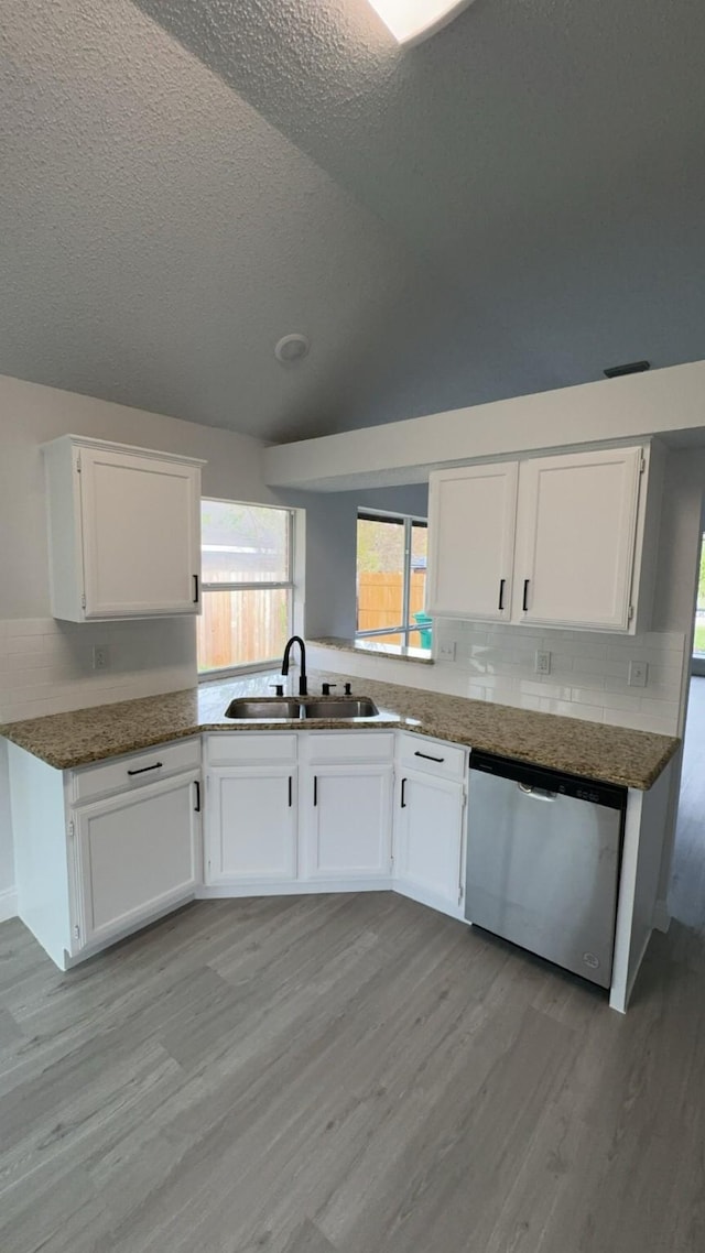 kitchen featuring white cabinets, light hardwood / wood-style flooring, stainless steel dishwasher, and sink