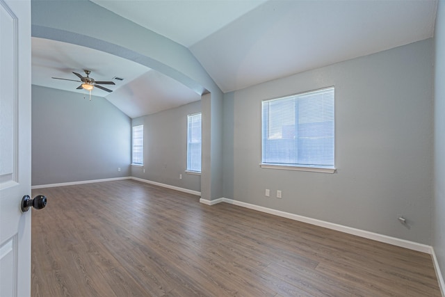 spare room with plenty of natural light, lofted ceiling, and dark wood-type flooring