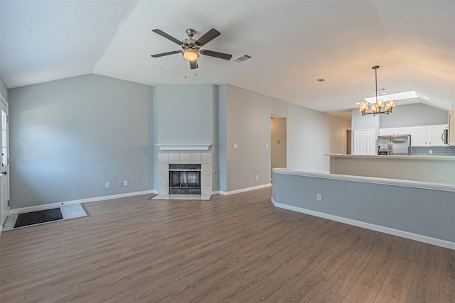 unfurnished living room featuring a fireplace, hardwood / wood-style floors, ceiling fan with notable chandelier, and vaulted ceiling