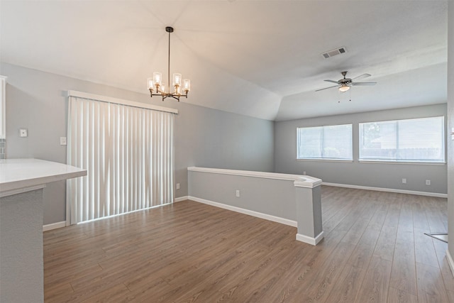 spare room featuring ceiling fan with notable chandelier, lofted ceiling, and hardwood / wood-style flooring