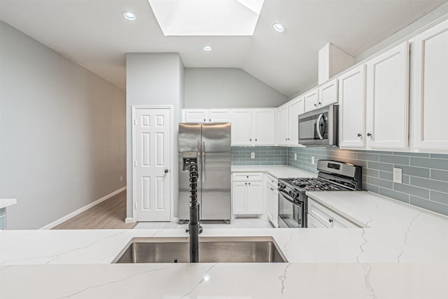 kitchen featuring light stone countertops, stainless steel appliances, and lofted ceiling